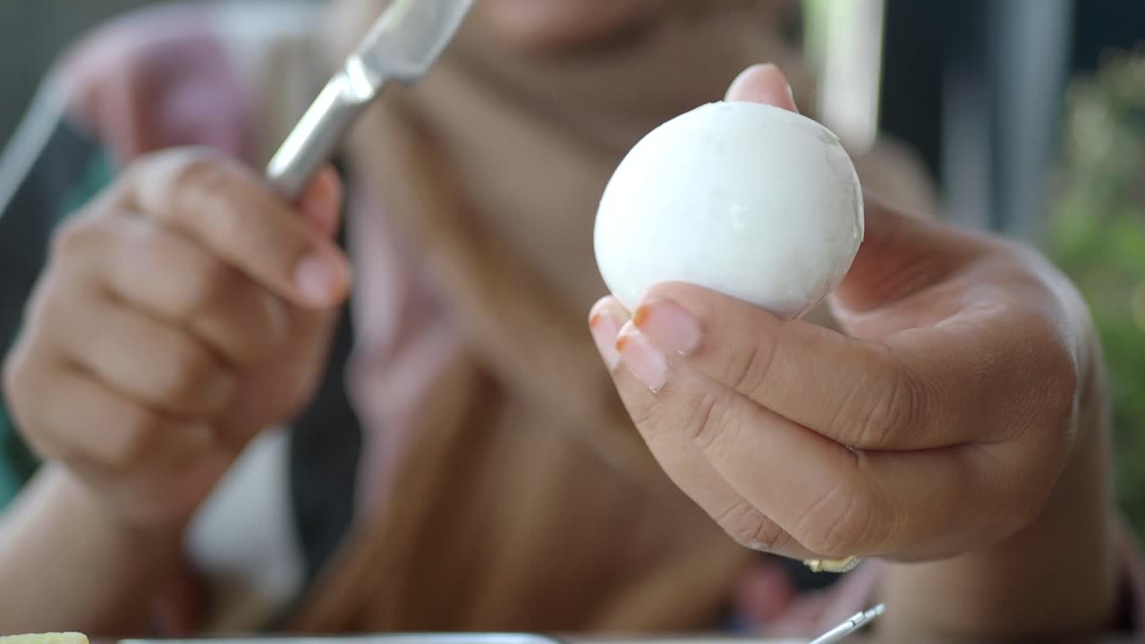 Person peeling a hard-boiled egg with a knife