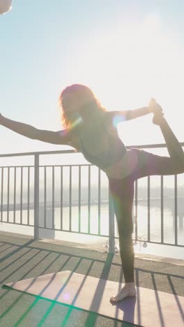 woman practicing yoga in a graceful pose with sunlight shining through the background