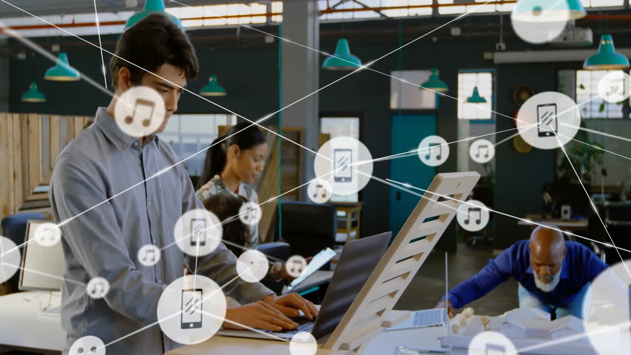 Working on laptops, diverse team with animation of digital network icons