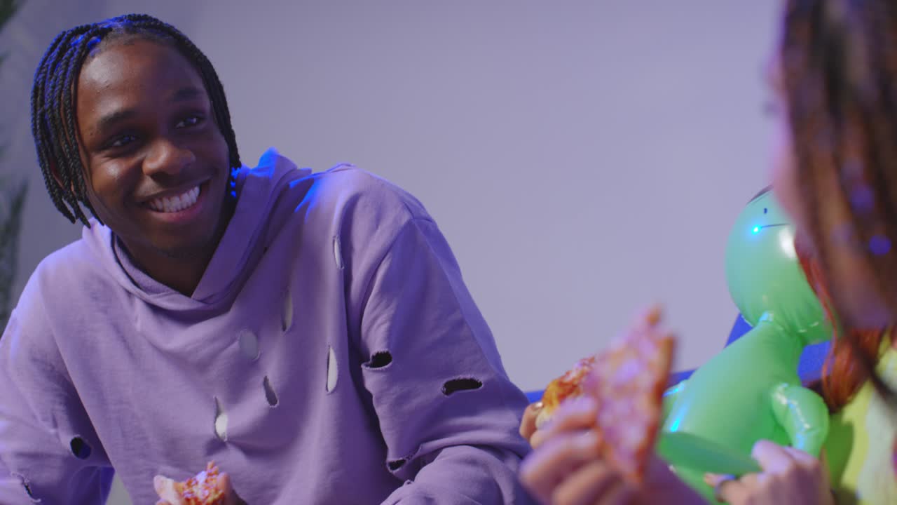 grupo de amigos de la generación z sentados en el sofá en casa comiendo pizza para llevar y hablando 2