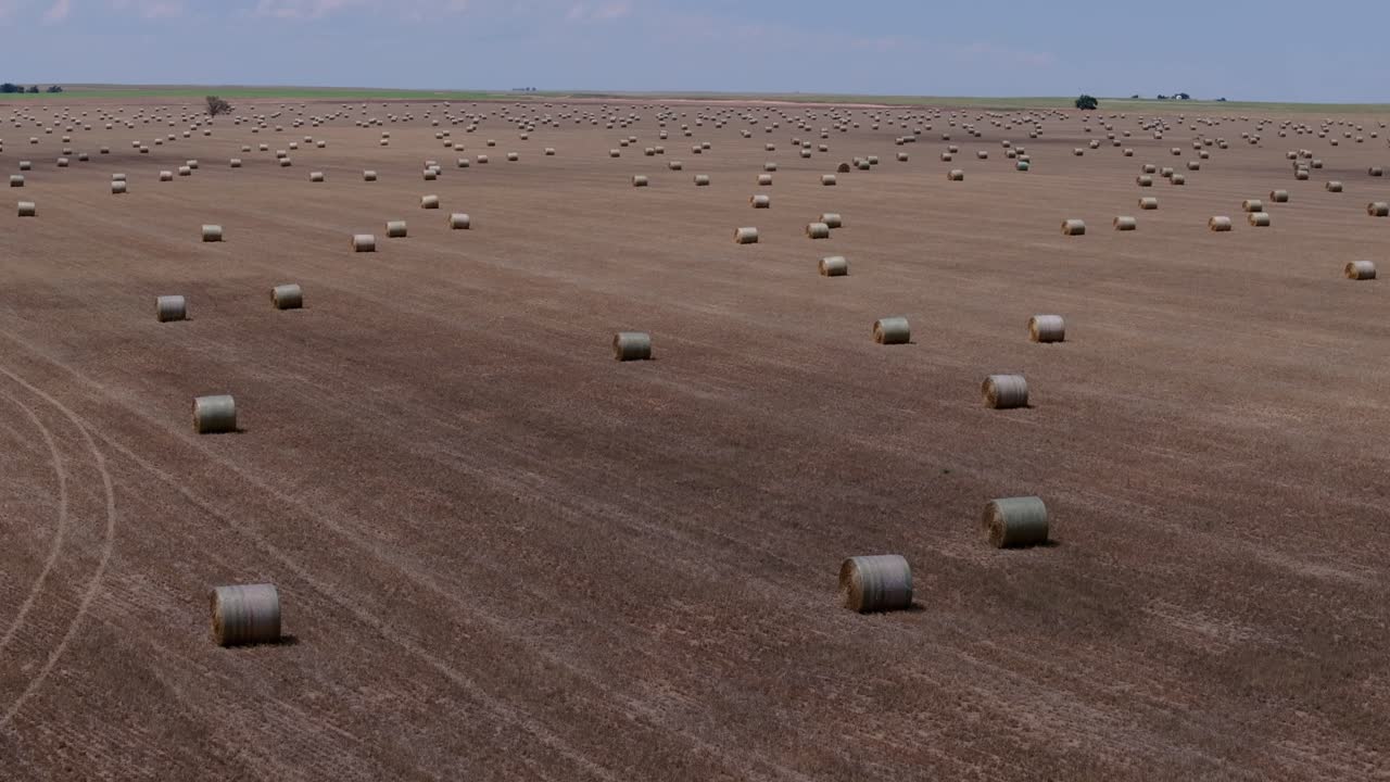 Wide drone view showing hay bales spread across vast Kansas countryside