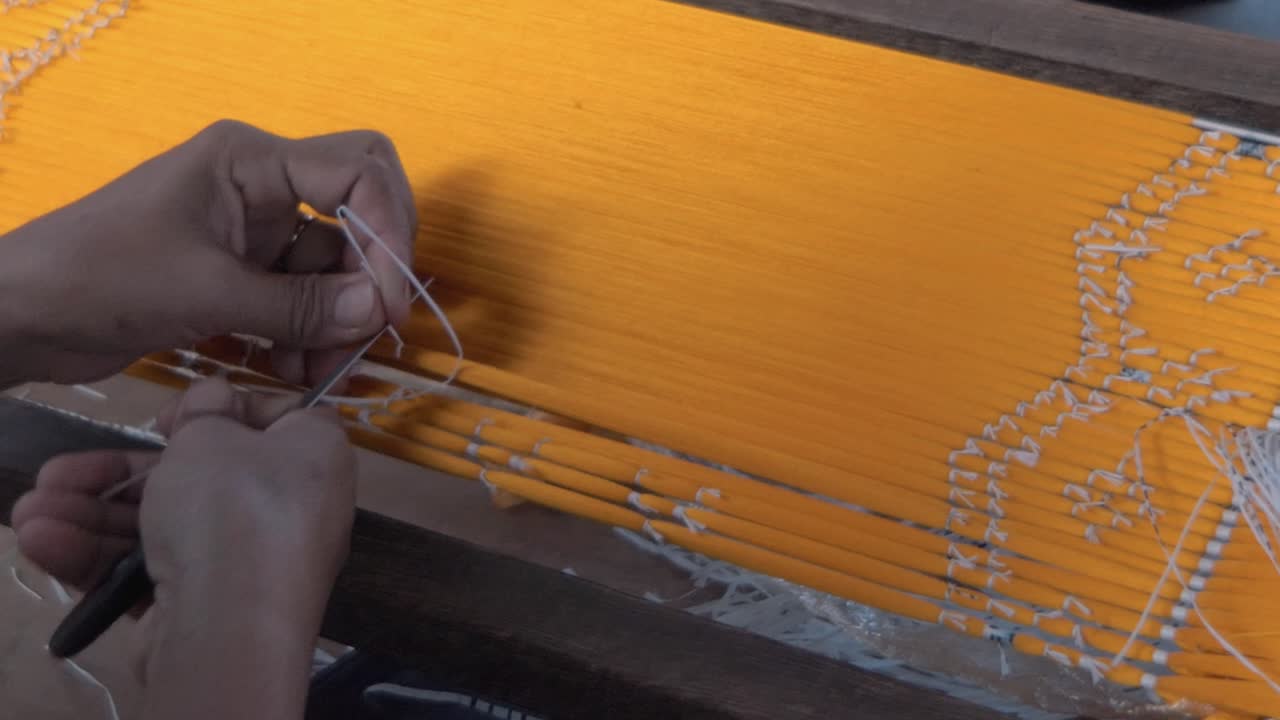 manos enhebrando seda con método ikat con aguja grande