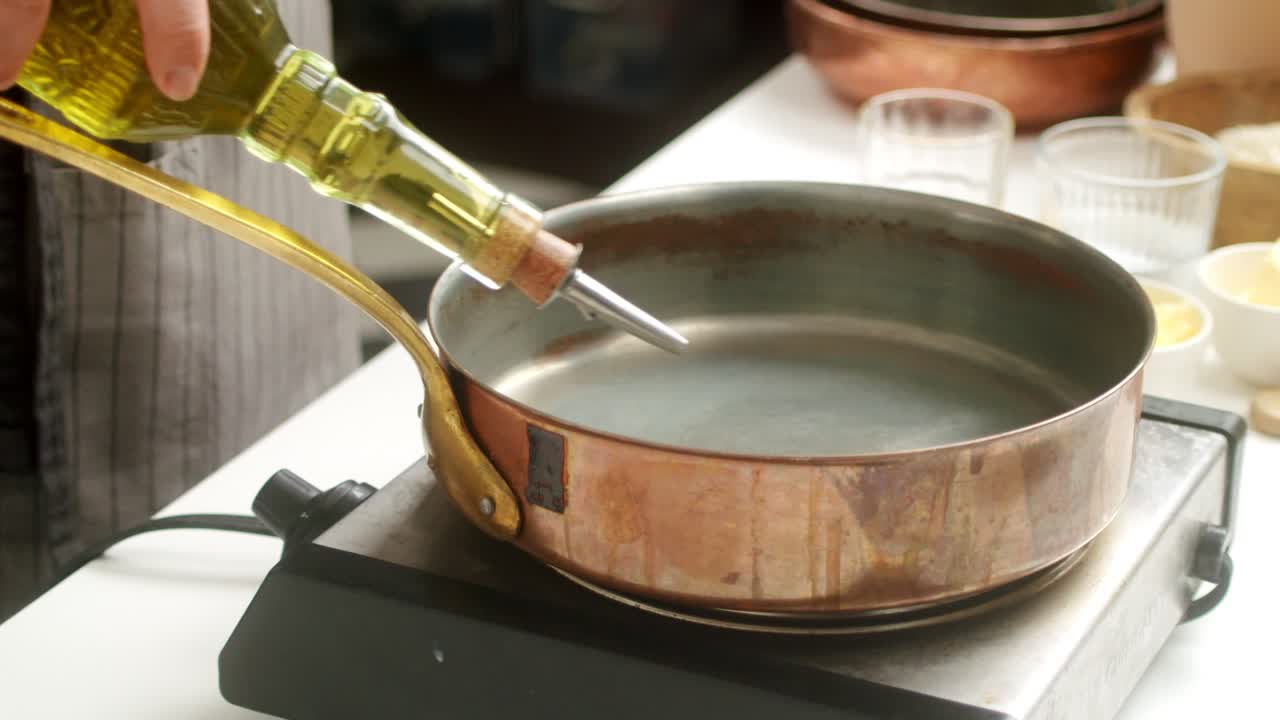 Crop cook adding oil on pan