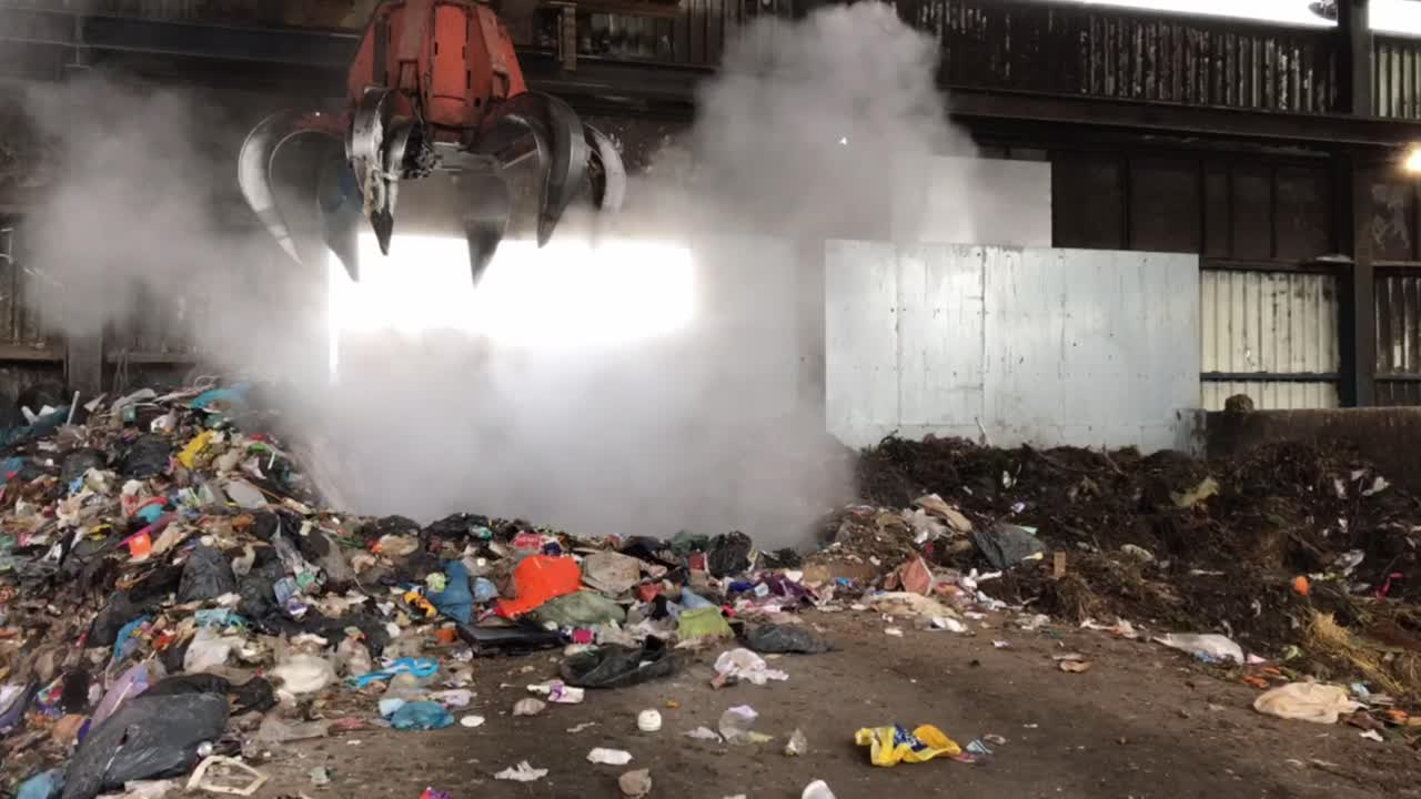 Crane dumps the waste in a press.