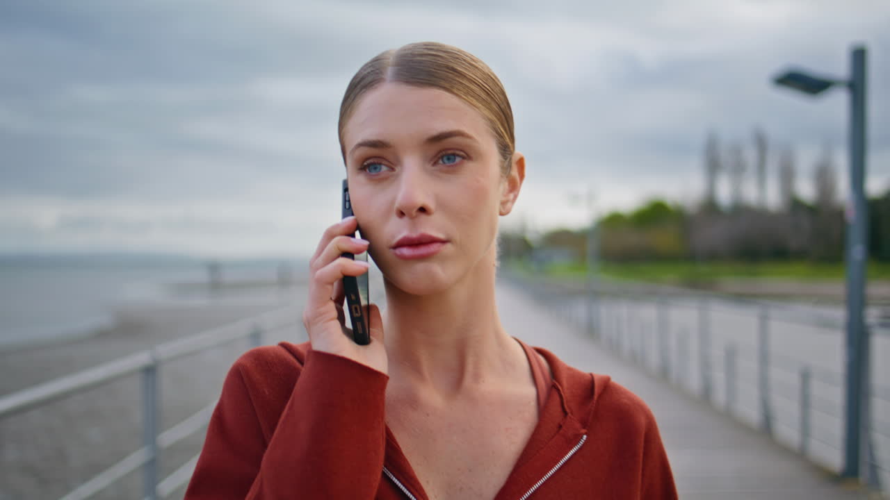 Casual woman communicating smartphone walking pier at coast. Closeup girl talk