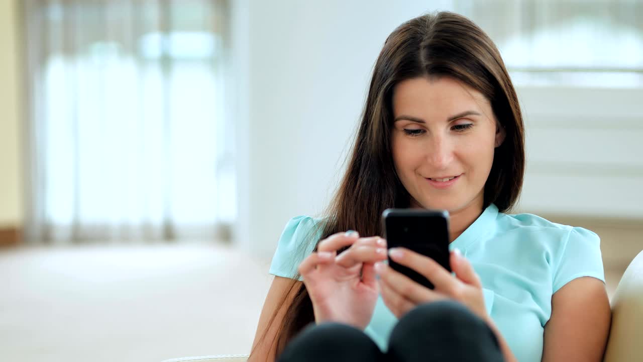 joven mujer de negocios sentada en el sofá y usando un teléfono inteligente. chica haciendo compras en línea, blogueando, revisando correo electrónico, chateando, mirando la pantalla