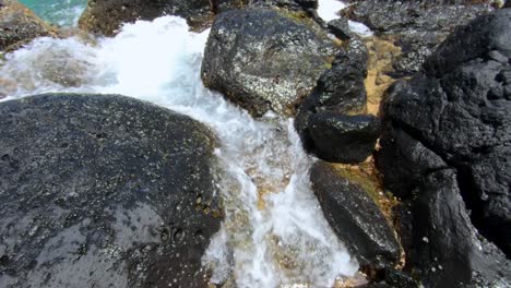pequeñas olas se lavan a través de grietas en la costa rocosa en hawaii
