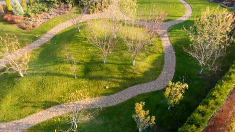 aerial drone view of backyard fruit garden with circle stone path, green grass lawn hills and trees. landscape design and gardening.