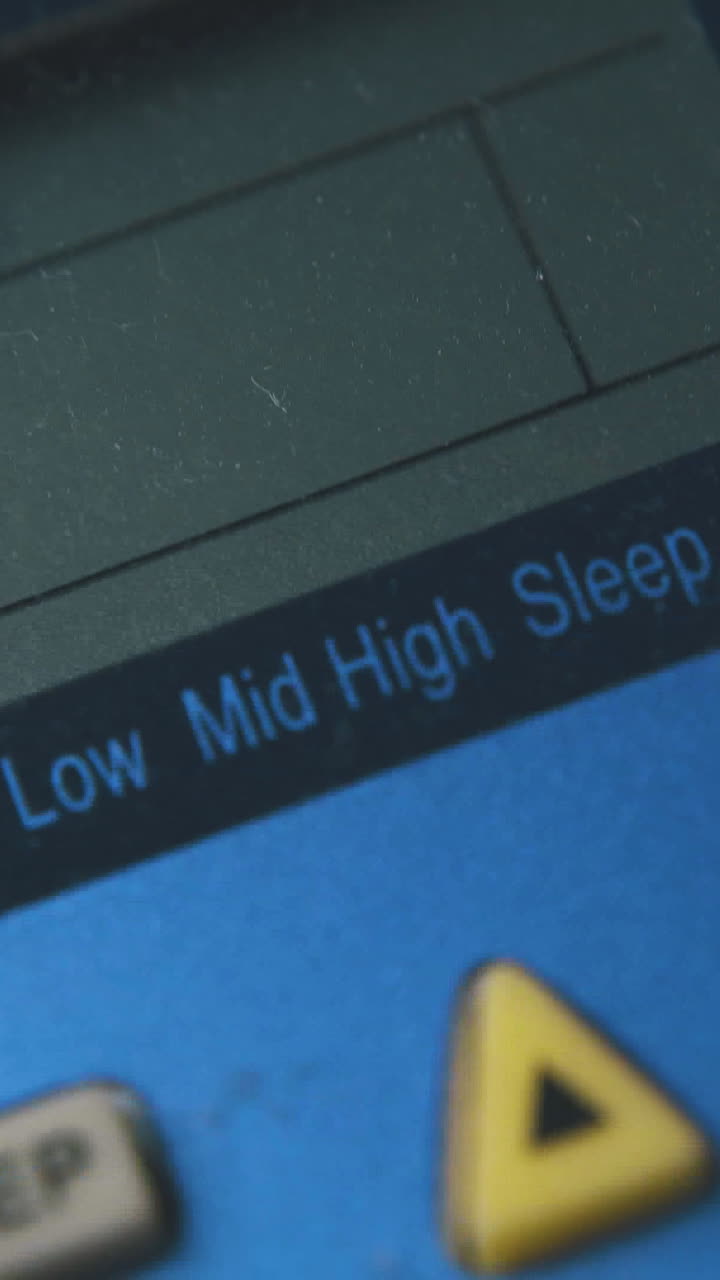 person lowers temperature pressing buttons on air conditioner remote control extreme close view