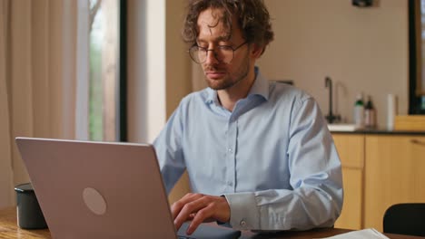 man working at home on laptop drinking coffee