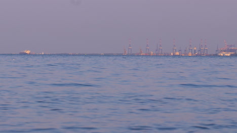 wide view of sea with industrial port cranes on horizon