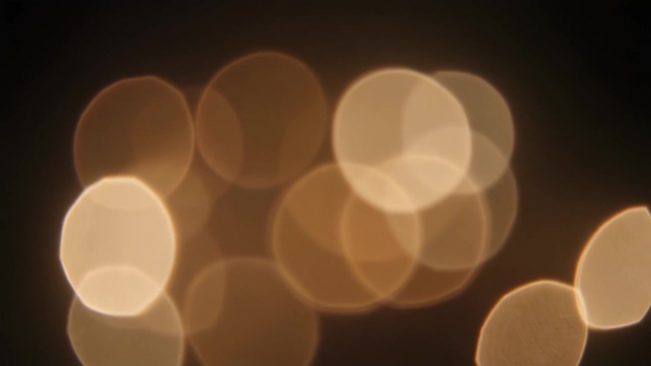 Luci Bokeh Dorate Astratte Scintillanti su Sfondo Scuro