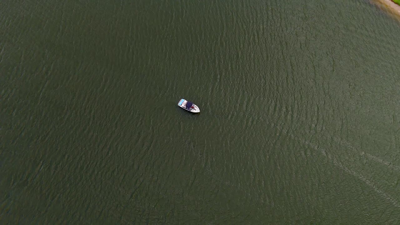 An aerial view of a motor speedboat on a lake, alone.