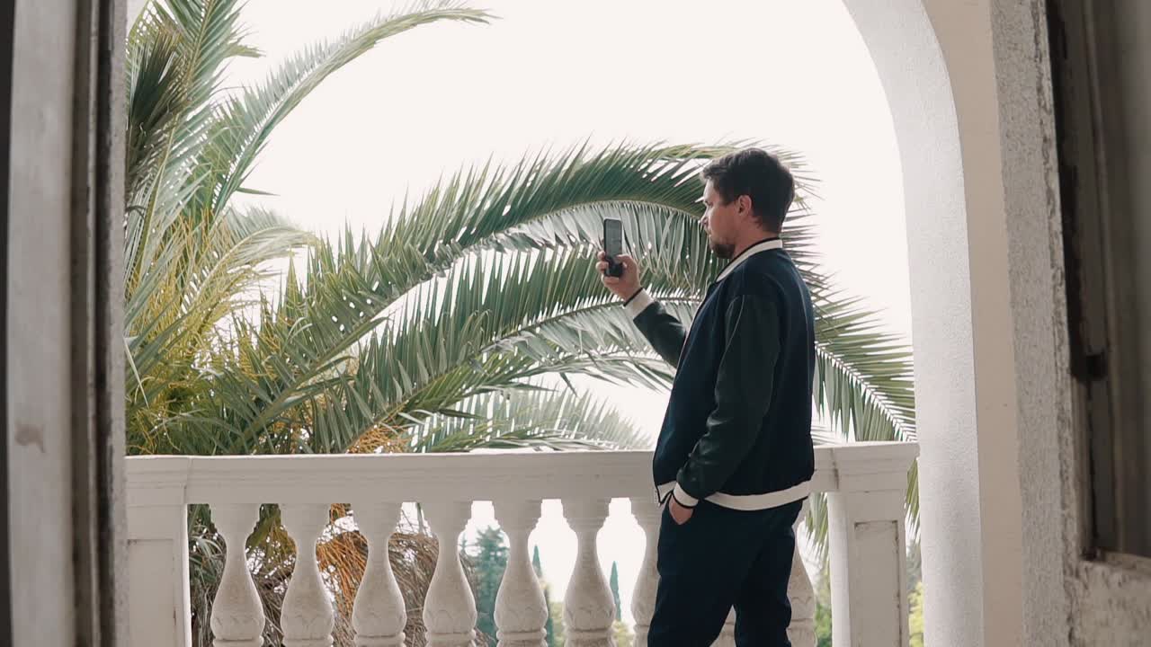 나무와 함께 발코니에서 셀피를 찍는 남자