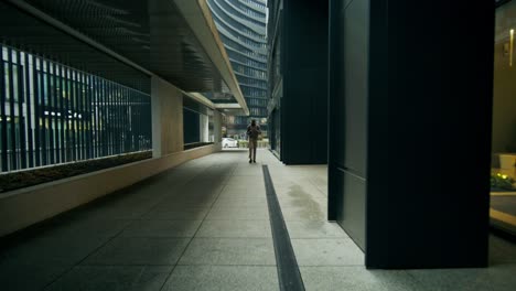 man walking through a city pathway between modern buildings