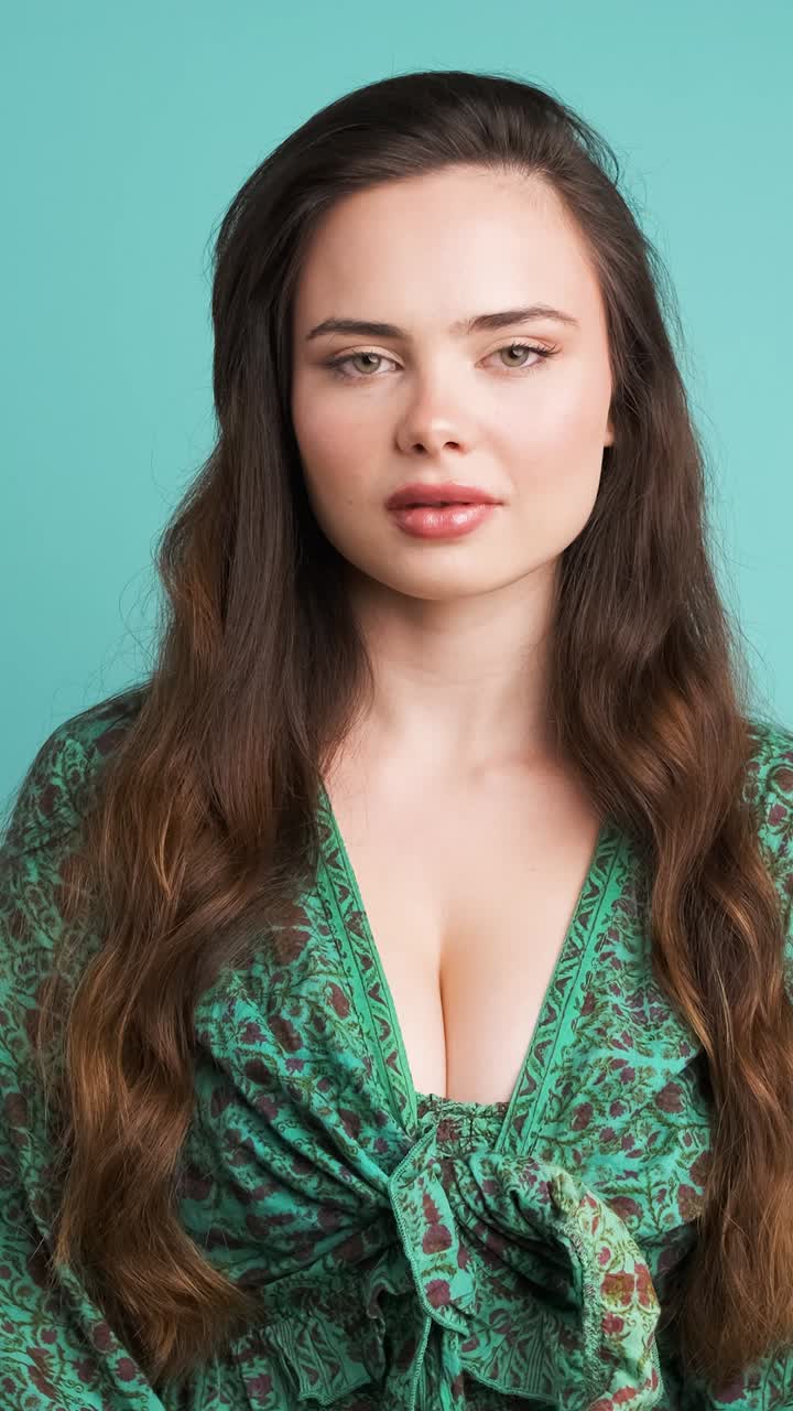 Shocked young woman covers mouth in blue studio