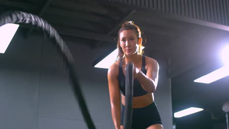 muscular sportswoman sportswear bodybuilder doing exercises with ropes in gym training muscles sport concept