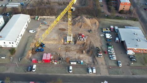 una gran grúa de construcción amarilla y varias máquinas de construcción se utilizan en un sitio de construcción