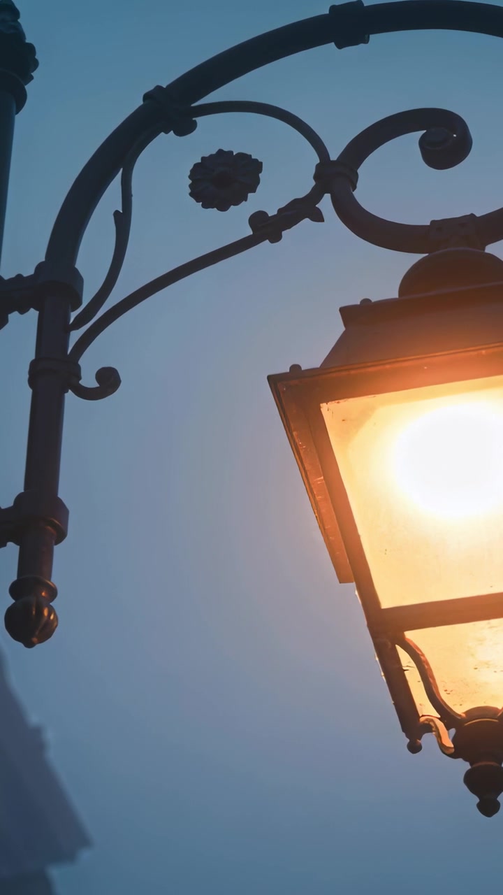 Video verticale: Lanterna in ghisa luminosa che illumina una strada al crepuscolo con un supporto curvo, spazio per il testo