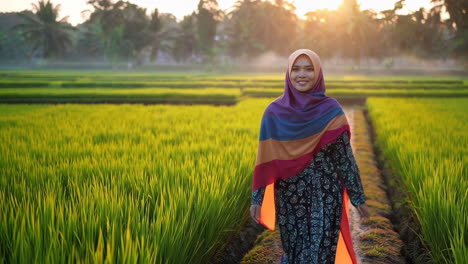 woman in hijab walking through a rice paddy at sunrise