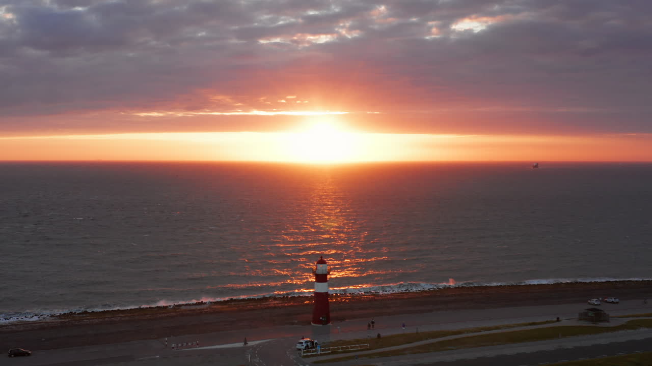 바람이 많이 부는 밝은 오렌지색 일몰 동안 웨스트카펠의 등대