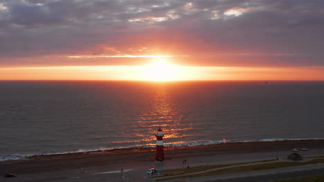el faro de westkapelle durante una puesta de sol naranja brillante, con mucho viento