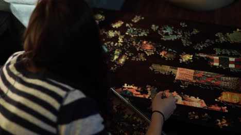 Over the shoulder shot looking for the best puzzle pieces spread across a smooth brown table