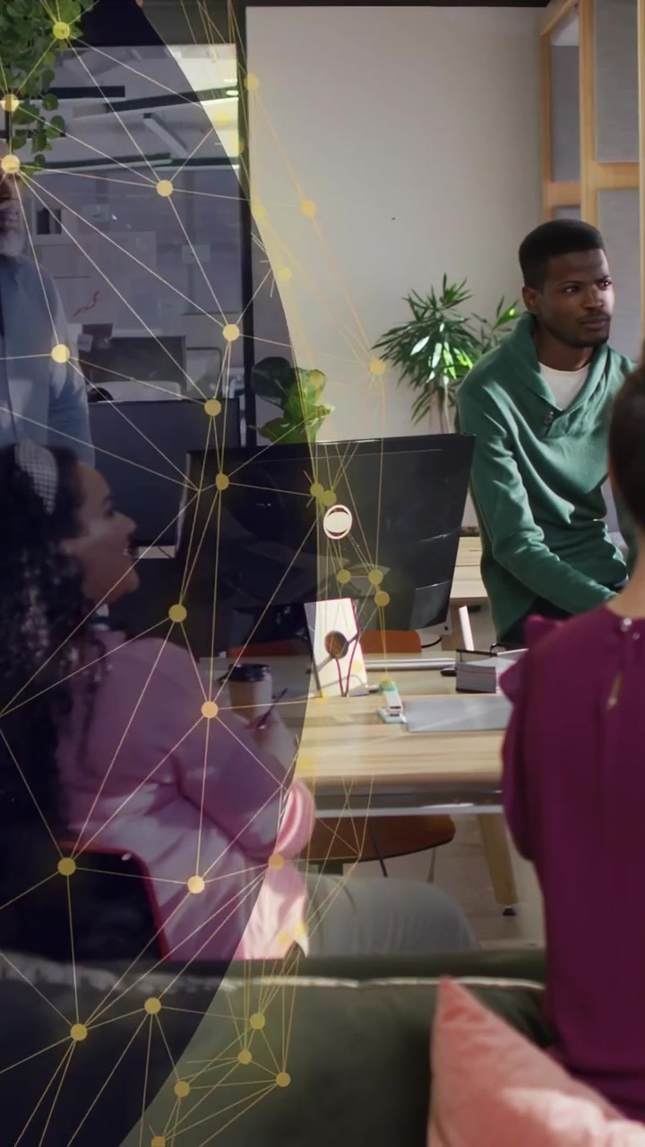Vertical video: Man in sweater watching business meeting, globe overlay shifting to reveal team