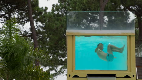 hombre buceando en una piscina de contenedores transparente