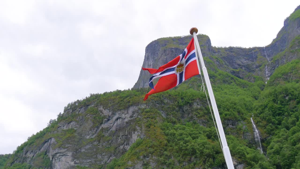 A 4K shot of a Norwegian flag blowing in the wind on a fjord cruise.