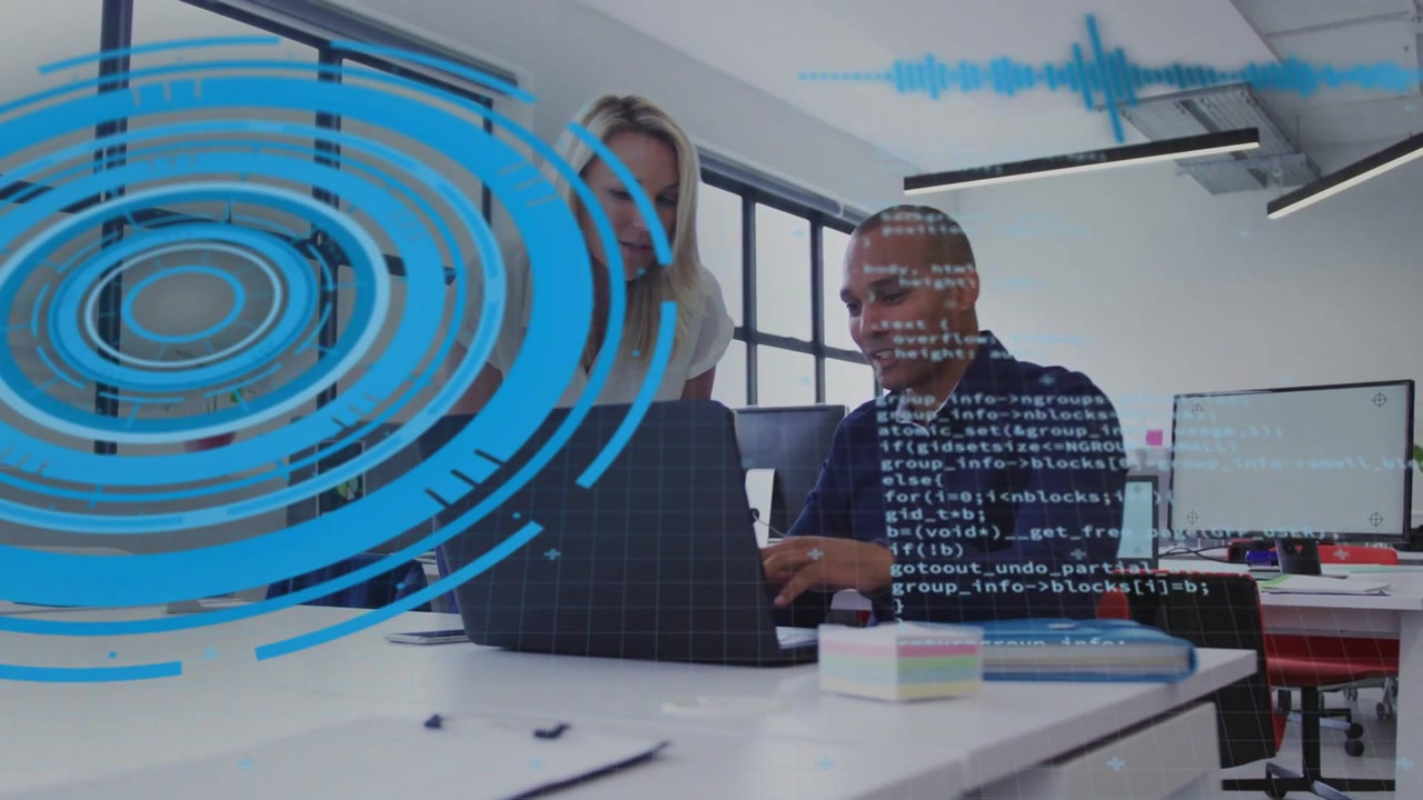 Man gesturing then typing while woman leaning over laptop, reviewing tech code with blue overlay