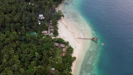 flying towards scenic island with palm forest and cottages at summer in san pablo island, southern leyte, philippines