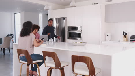 hombre negro llegando a casa con su familia en la cocina con bolsas de compras