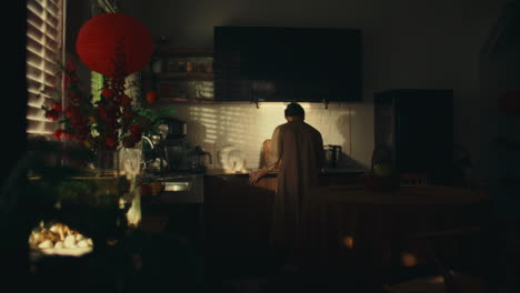 elderly woman standing alone in a dimly lit kitchen, evoking solitude and nostalgia