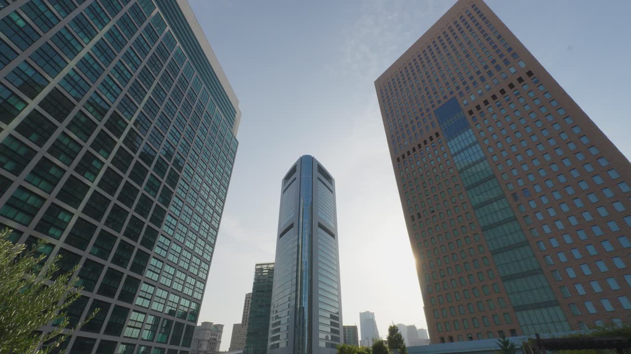 A view of three distinct modern skyscrapers in Tokyo, their facades reflecting the bright sun