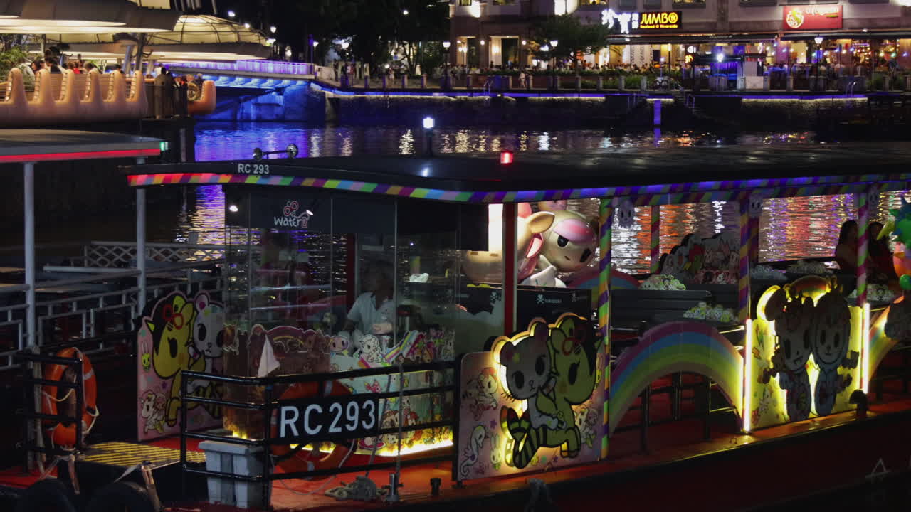 Colorful lights illuminating buildings and sightseeing boats at night in Clarke Quay