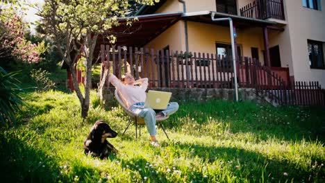 a young adult woman working on her laptop while sitting in the garden