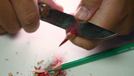 Footage-of-hands-slowly-sharpening-a-pencil-and-some-coloured-pencils-with-a-sharp-knife