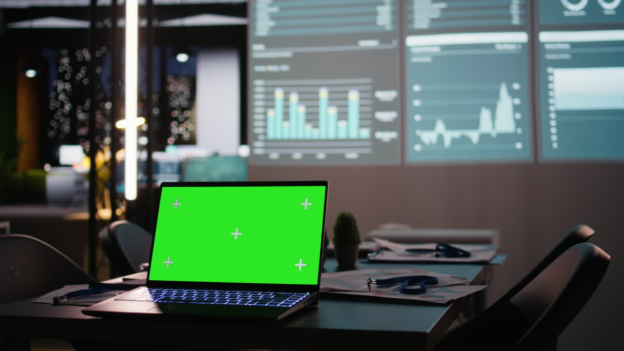 After hours office space with mockup laptop and a glowing analytics display