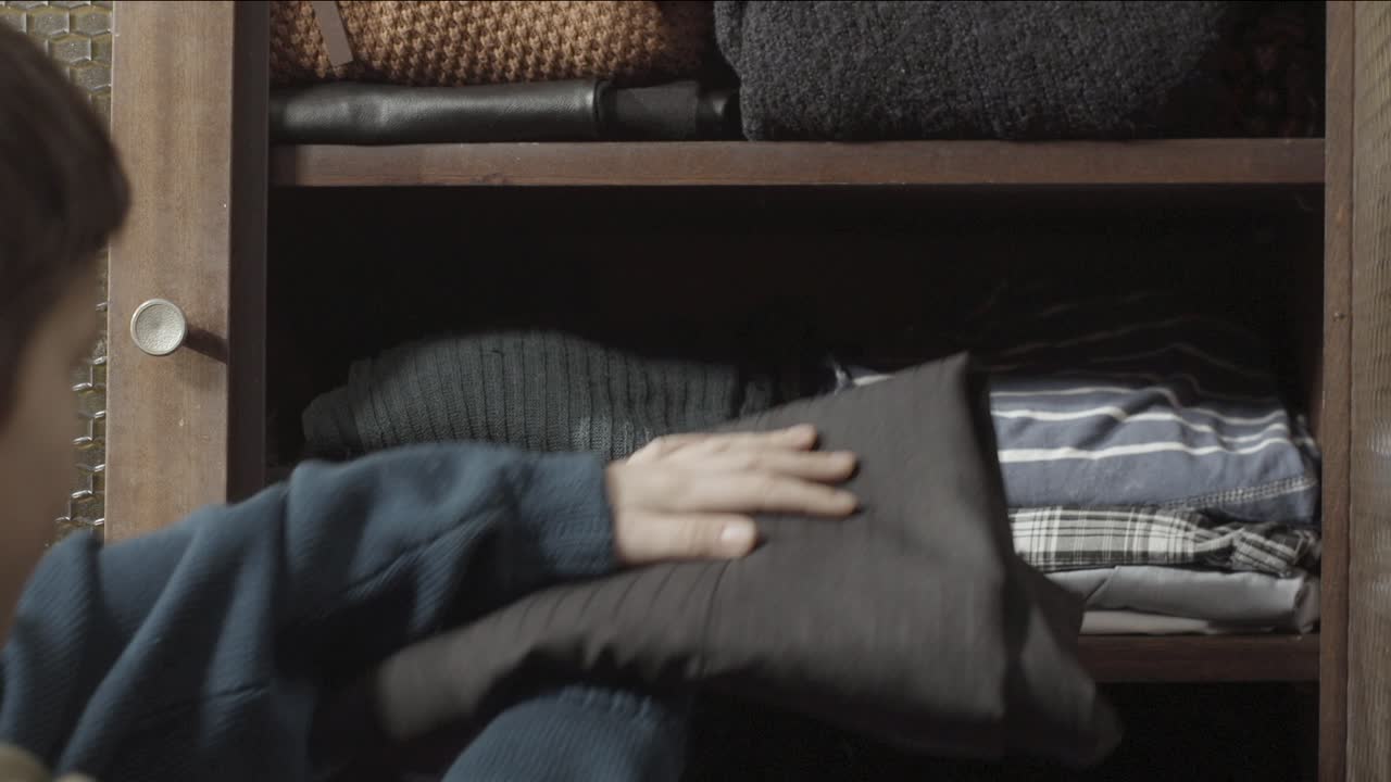 Child organizing clothes in a closet