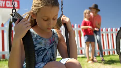 upset girl sitting on a swing while friends talking in the background 4k