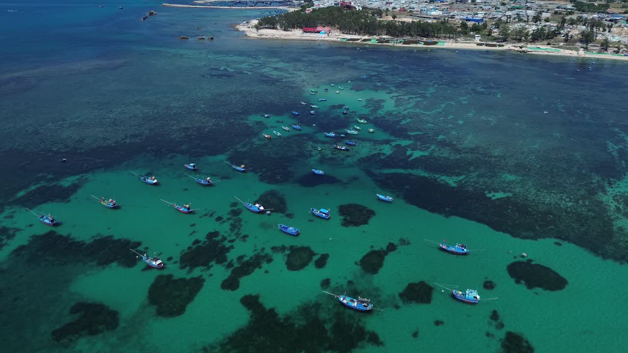 Zoom in aerial view of clustered fishing boats anchored in shallow turquoise waters, Phan Rang in Ninh Hải District, Ninh Thuận, Vietnam