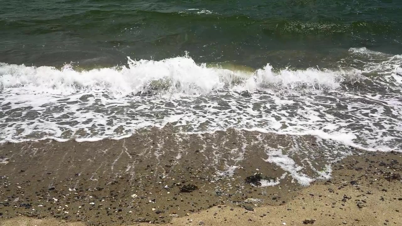 Onde oceaniche rilassanti con schiuma bianca che si infrangono su una spiaggia sabbiosa. Onde leggere che si infrangono su una costa tranquilla, creando uno sfondo rilassante.