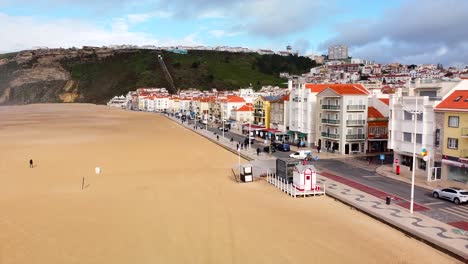 aerial along nazare beach promenade. slow ascending shot