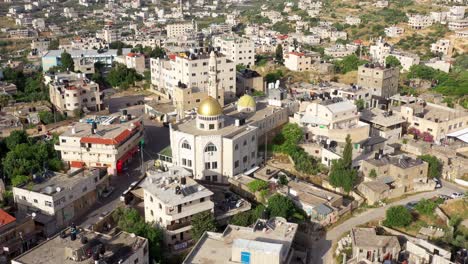 aerial view of a middle eastern town with a prominent mosque featuring golden domes