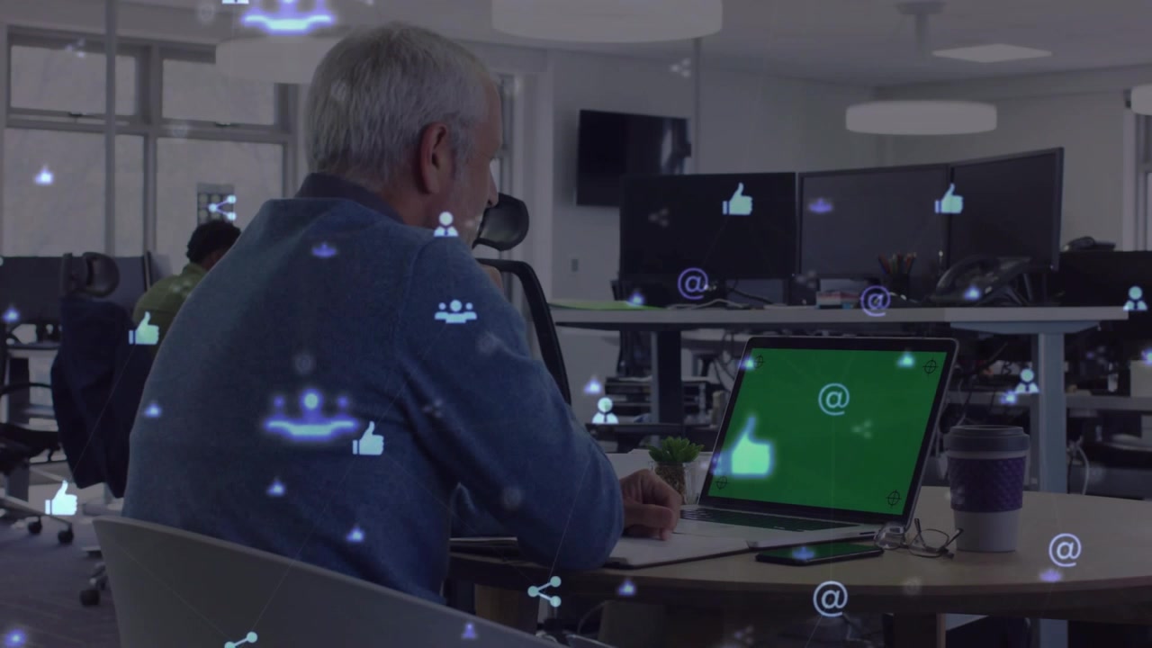Uomo seduto che scrive in un ufficio tecnologico, mentre un'icona di laptop attira lo sguardo e icone social si sovrappongono.