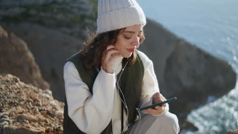 relaxed girl listen music on ocean cliff vertical. stress free traveler resting