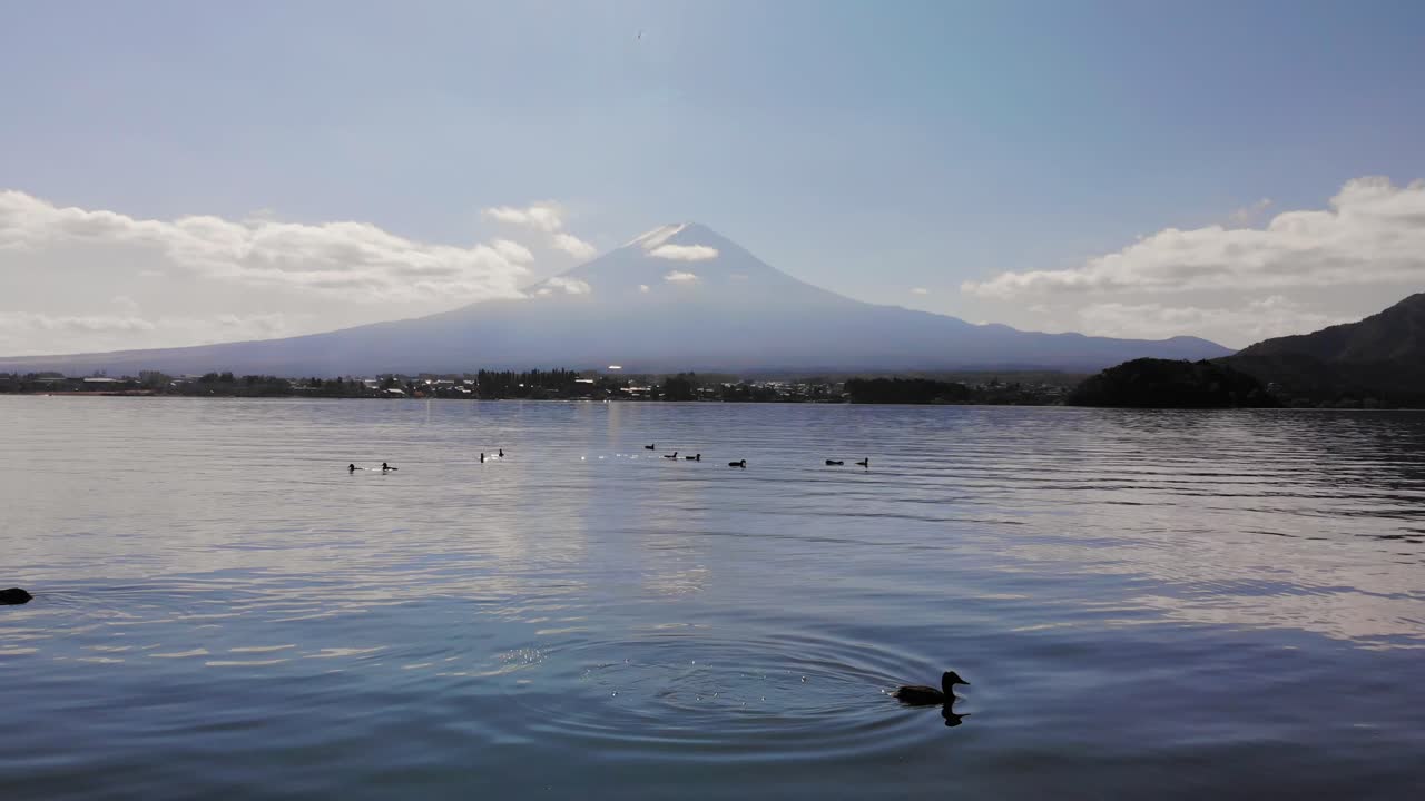 Dron avanzando cerca del agua con patos y el Monte Fuji de fondo.