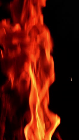 beautiful red fire burning at night. little sparkles fly up from the flame. close up. vertical video