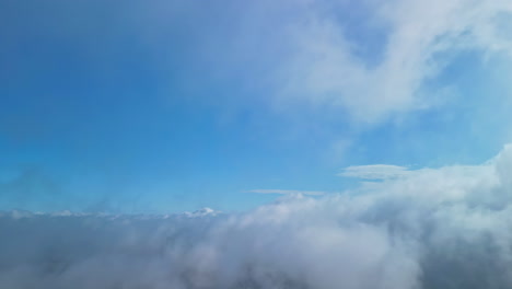 a drone flies through a cloudscape on a blue sky day